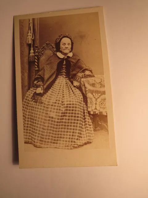 sitting old woman in mature skirt with cloak hood - backdrop circa 1860s / CDV