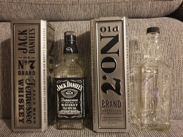 Zwei Jack Daniels Sammeldosen aus Blech in Farbe Silber mit zwei leeren Flaschen