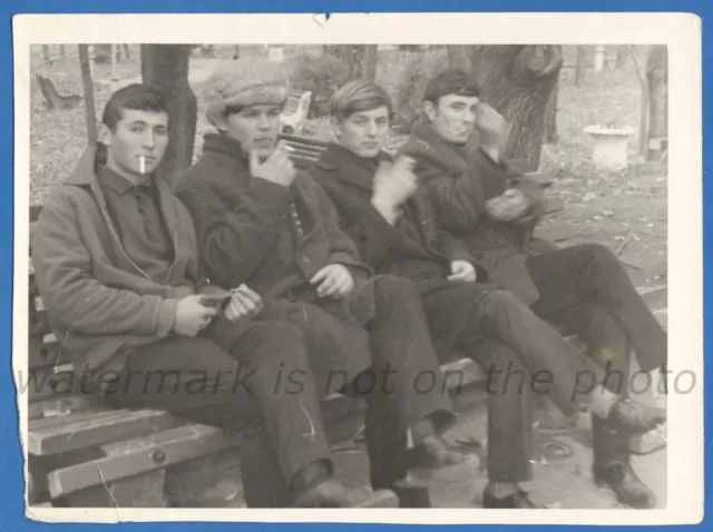 Handsome guys are sitting on a bench and smoking cigarettes Vintage photo