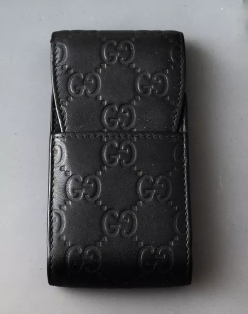 GUCCI MONOGRAM PHONE/CIGARETTE HOLDER, dark leather trims and flap snap  closure with iconic GG logo, fabric lining, 19cm x 12cm and a similar card  holder and a Piaget black leather wallet. (3)