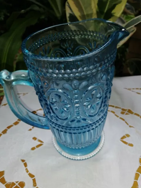 https://www.picclickimg.com/3c4AAOSwQOBiS9Ys/Pressed-Footed-Blue-Glass-Water-Jug-Pitcher-Embossed-with.webp