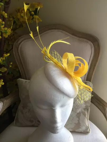 Gorgeous white coloured round fascinator yellow loops, feathers and netting.