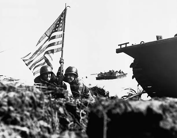 Two US Soldiers plant an American flag attached to boat hook beach - Old Photo