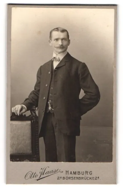 Fotografie Otto Haase, Hamburg, Portrait junger Herr im Anzug mit Fliege an Stu