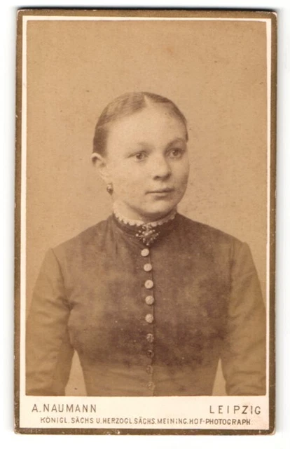 Fotografie A. Naumann, Leipzig, junge lächelnde Frau im dunklen Kleid mit Brosc