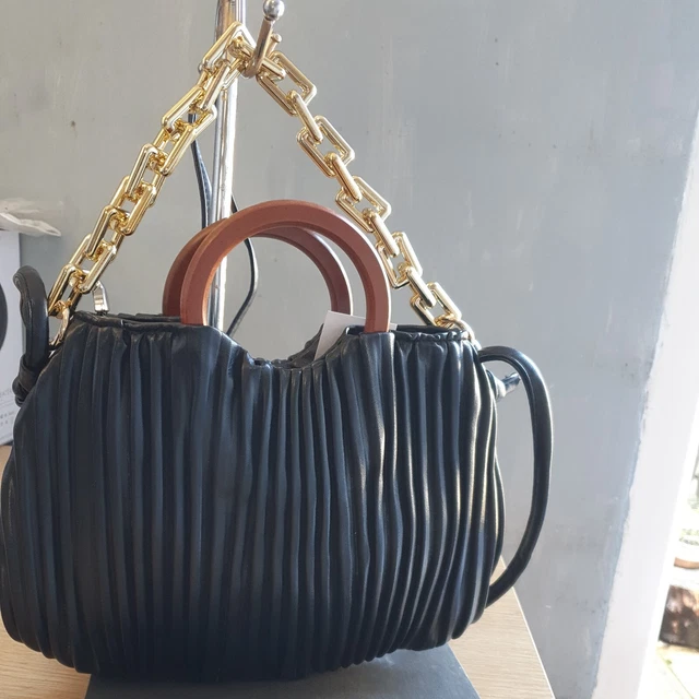 Damenhandtasche. Schwarz. Reißverschluss. Falten. Griff mit Holzeffekt. Falten. Goldglieder