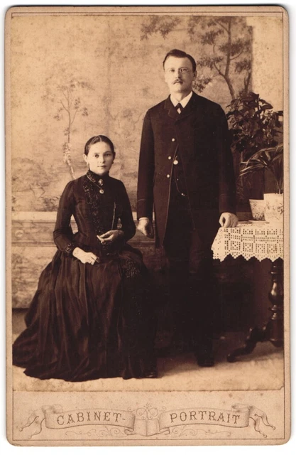 Fotografie unbekannter Fotograf und Ort, Herr mit Brille und sietzende Dame in