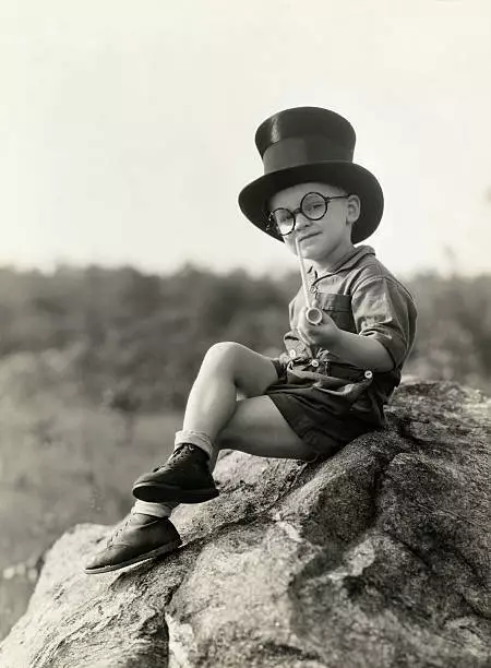 Small Child Sitting On A Rock With A Clay Pipe, Top Hat And Round - Old Photo