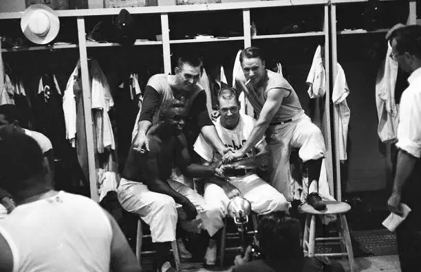 Brooklyn Dodgers Jackie Robinson in the locker room posing with te - Old Photo