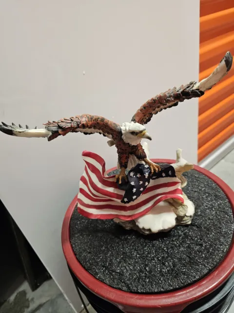 Patriotic American Bald Eagle Perched On Rock Holding Flag Ceramic Statue