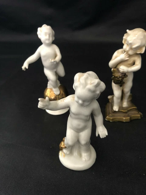 3 Puttis ; sur globe doré en porcelaine allemande, au crabe doré, aux raisins
