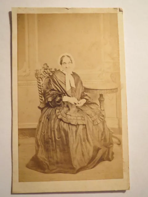 Backdrop seated old woman in mature skirt with hood - circa 1860s / CDV
