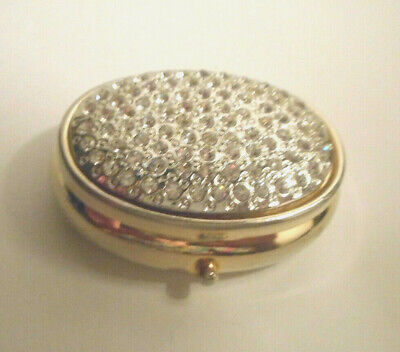 Gold tone oval trinket box studded with rhinestones on top & a dimpled bottom