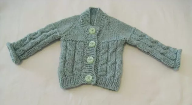 baby's hand-knitted part-cabled round-neck cardigan in green to fit prem baby