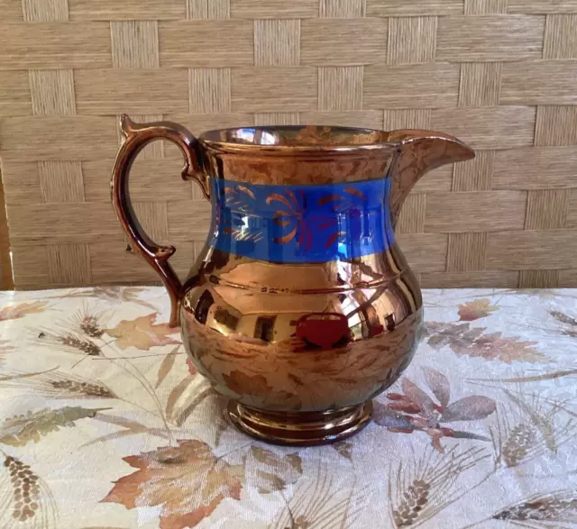 Antique copper lusterware pitcher with ornate handle, blue band. 5.5 inches.