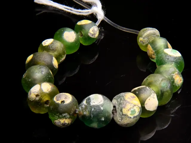 A Short Strand of 15 Ancient Islamic Period Green Evil Eye Beads with Yellow and