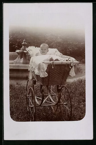 Foto-AK Lächelnder kleiner Junge im Kinderwagen vor einem Brunnen