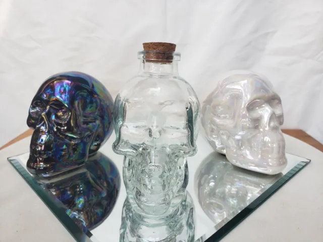 Pair of  Ceramic Skull Figurines & 1 Glass Skull Bottle Complete w/ Cork Stopper