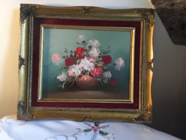 A still life oil painting of roses in a vase, beautifully framed.