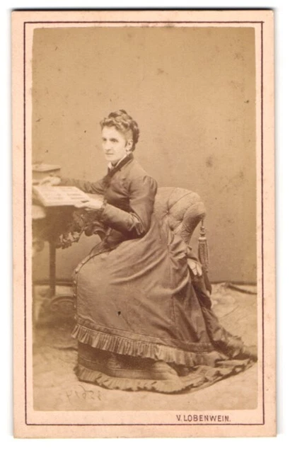 Fotografie V. Lobenwein, Klagenfurt, Dame im Gründerzeitkleid blättert in einem