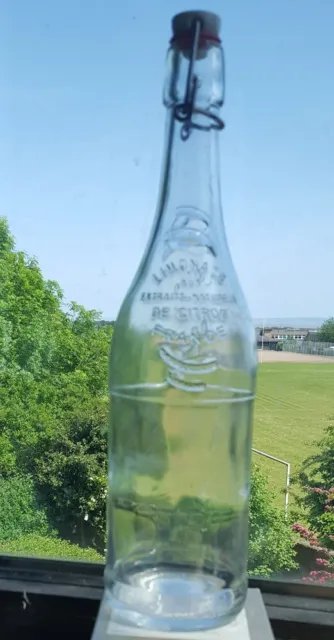 Clear glass round lemonade bottle with embossed words and swing top from France.