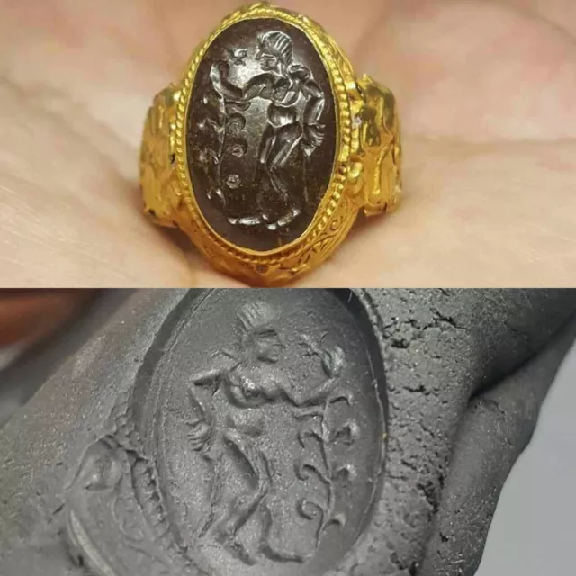 Roman style gold intaglio ring with a large engraved garnet showing woman holdin