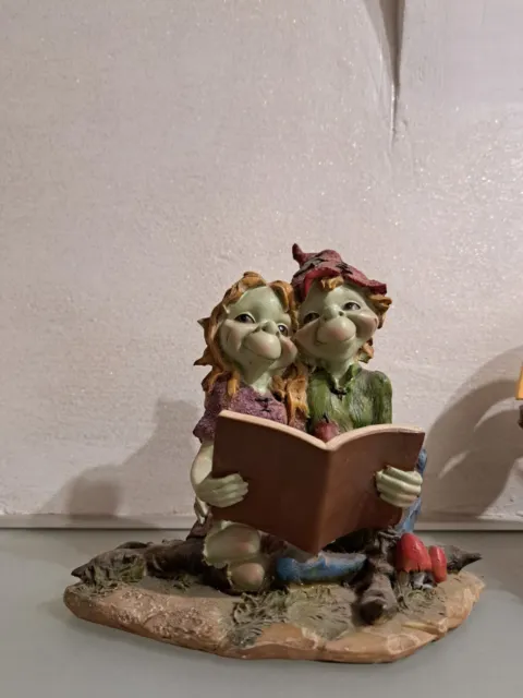 Statuetta raffigurante una coppia di folletti Pixie seduti a leggere