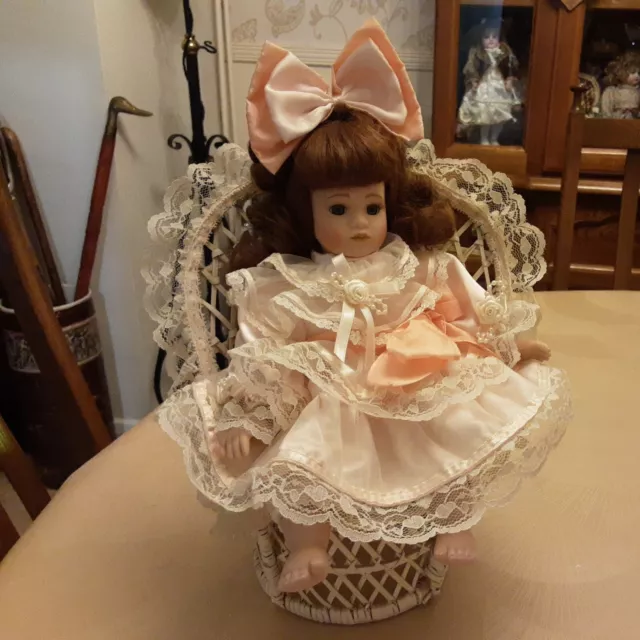 Cute Little Porcelain Doll In Wicker Chair. Leonardo Collection