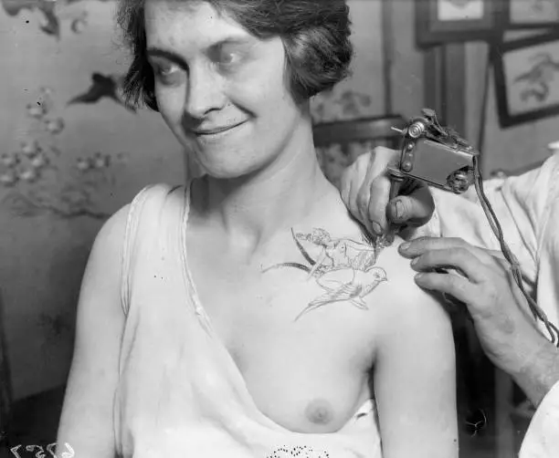 Woman having her shoulder tattooed with a goddess and a bird; a st- 1930s Photo