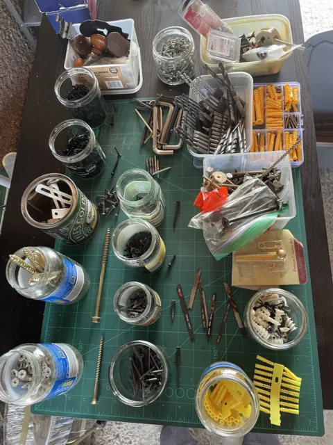 Variedad de tornillos, tapones, hardware, herramientas, cuchillas, llaves hexagonales, taladros, caja de plástico