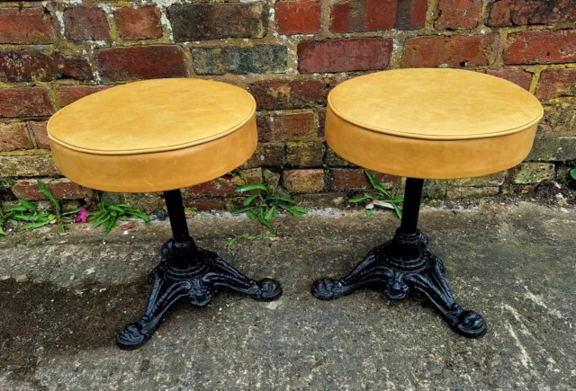 A pair of vintage cast iron stools with leather seats