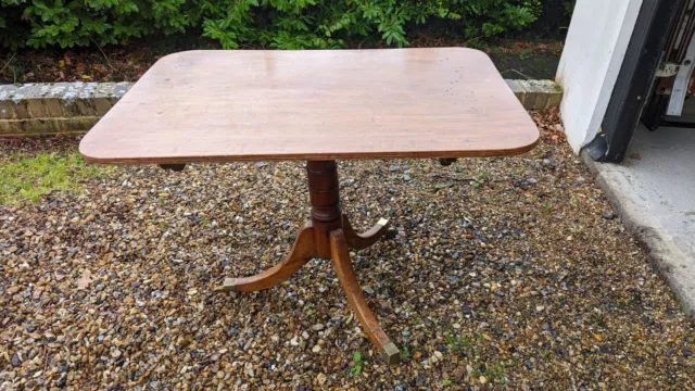 Antique wooden flip top table. Three metal-tipped feet on castors