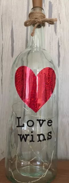 lighted wine bottle With ‘Love wins’ logo and  metallic red heart 