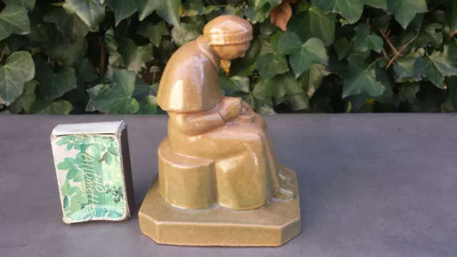 Sujet en terre cuite vernissée signé. Vieille dame assise mangeant la soupe
