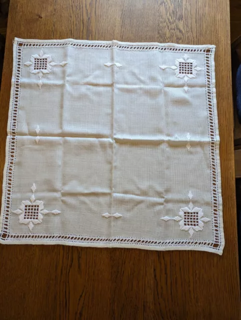 Square Table cloth, cream, with embroidered corner pattern and edging.