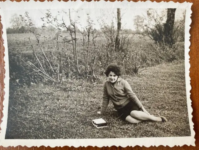 Beautiful young woman sitting on the grass, posing for the camera Vintage photo