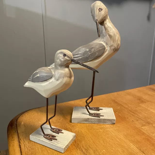 A pair of wooden hand carved painted shorebird metal legs beach sea