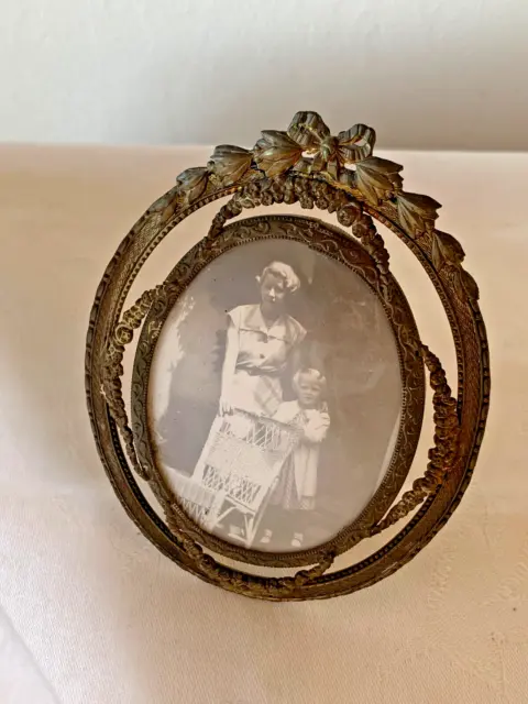 Antique brass oval photo frame with easel back, ribbon and floral accents