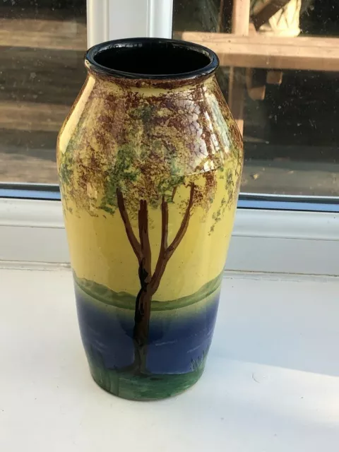 old decorated torquay vase ! trees by a river or sea .