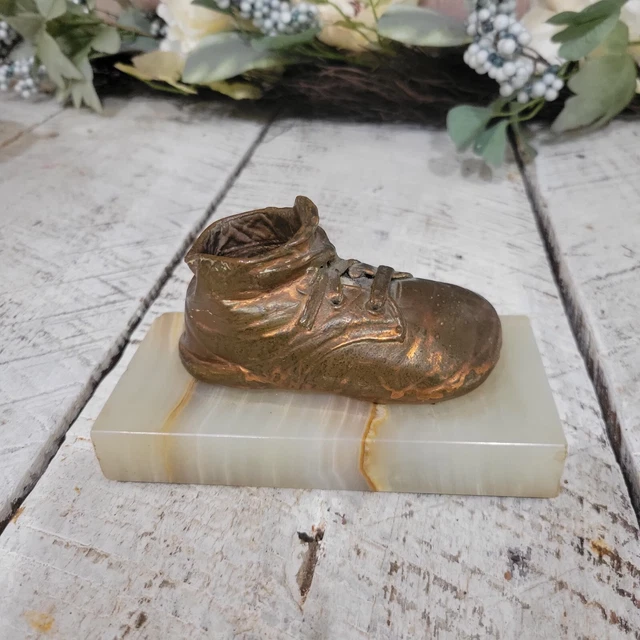 Zapatos de bebé de bronce vintage sobre base de mármol decoración infantil