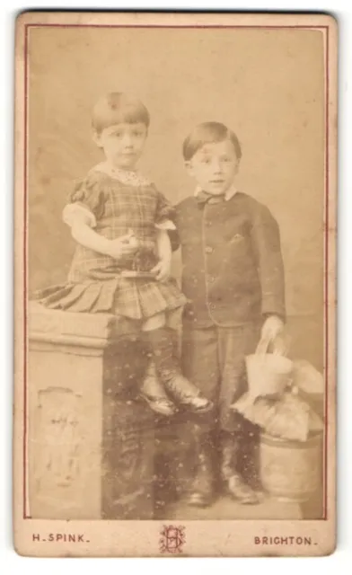 Fotografie H. Spink, Brighton, Kleines Mädchen in kariertem Kleid sitzt auf Säu