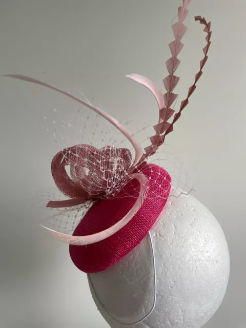 Hot Pink fascinator with round base and pink loops, netting and feathers.