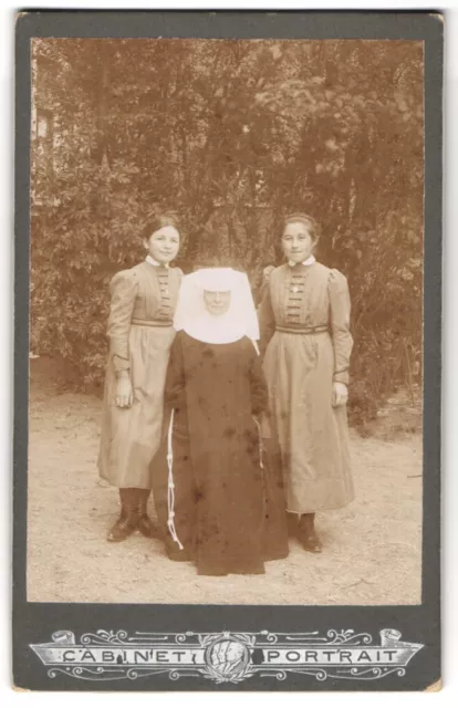 Fotografie ältere Nonne im Habit mit Haube und zwei jungen Mädchen
