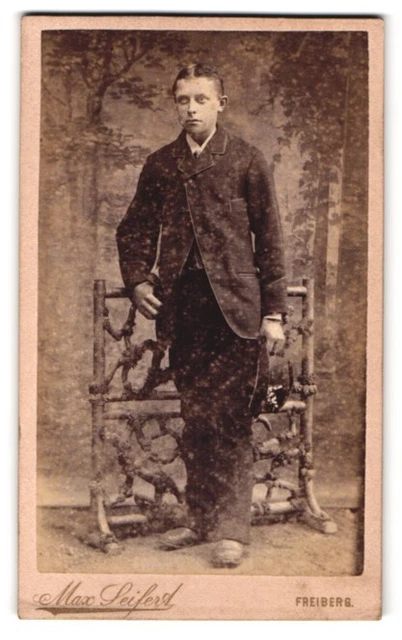 Fotografie Max Seifert, Freiberg, Neugasse, Bursche im Anzug mit Hut vor Kuliss
