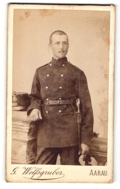 Fotografie G. Wolfsgruber, Aarau, Portrait Soldat in Uniform mit Tschako und Ba