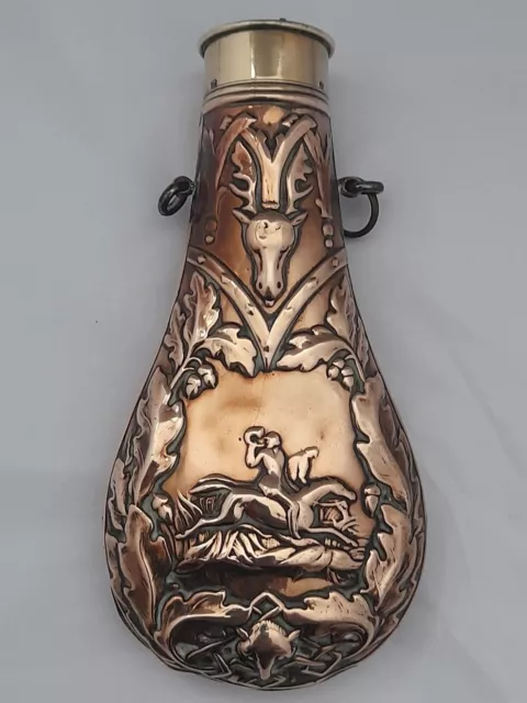 Antique brass and copper powder flask decorated in repousse with a hunting scene