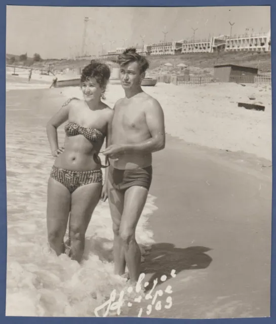 Tender boy in swimming trunks and girl in swimsuit on the beach, naked torso