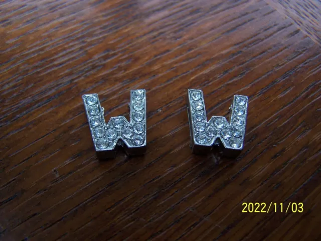 Bouton ancien en strass sur métal argenté en forme de lettre. Lettre W. Réf 415