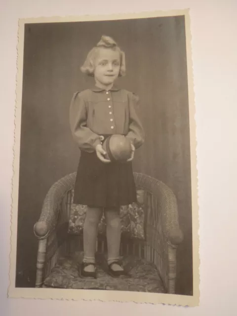 standing little girl in skirt with toy ball in hand - 1942 / photo