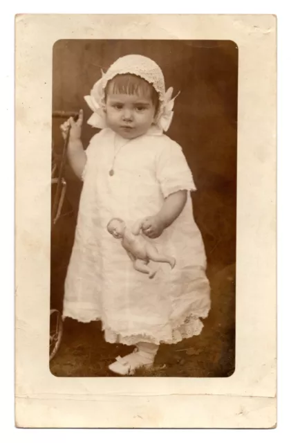 RPPC POSTCARD CIRCA 1920s CUTE LITTLE GIRL IN WHITE DRESS HOLDING TOY DOLL